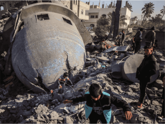 Young Palestinians standing amidst the ruins of a destroyed mosque caused by israeli air strike