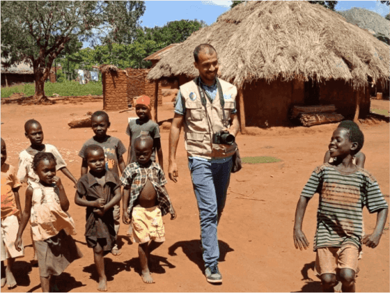 A group of playful and happy children in Africa with a Sabili Foundation member
